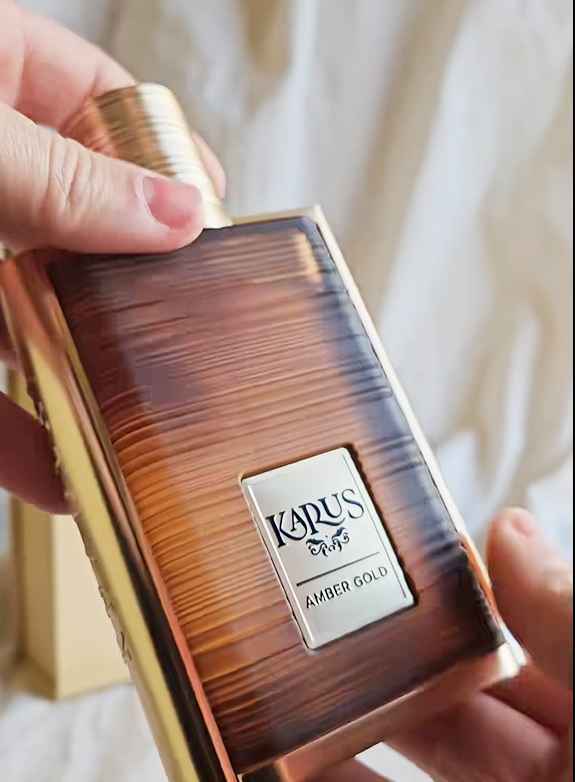 Khadlaj Karus Amber Gold frasco sostenido en mano sobre fondo neutro
