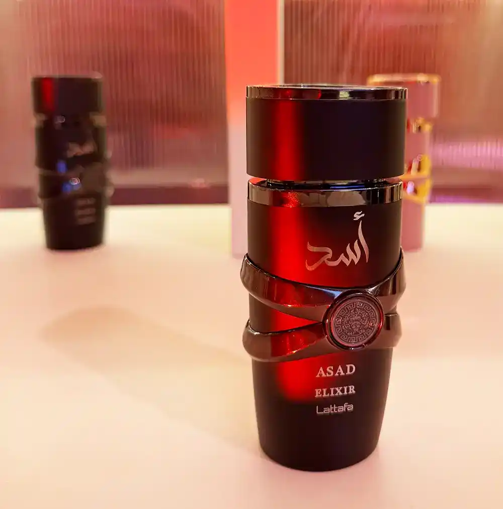 Lattafa Asad Elixir frasco y caja colocados sobre mesa con caja abierta