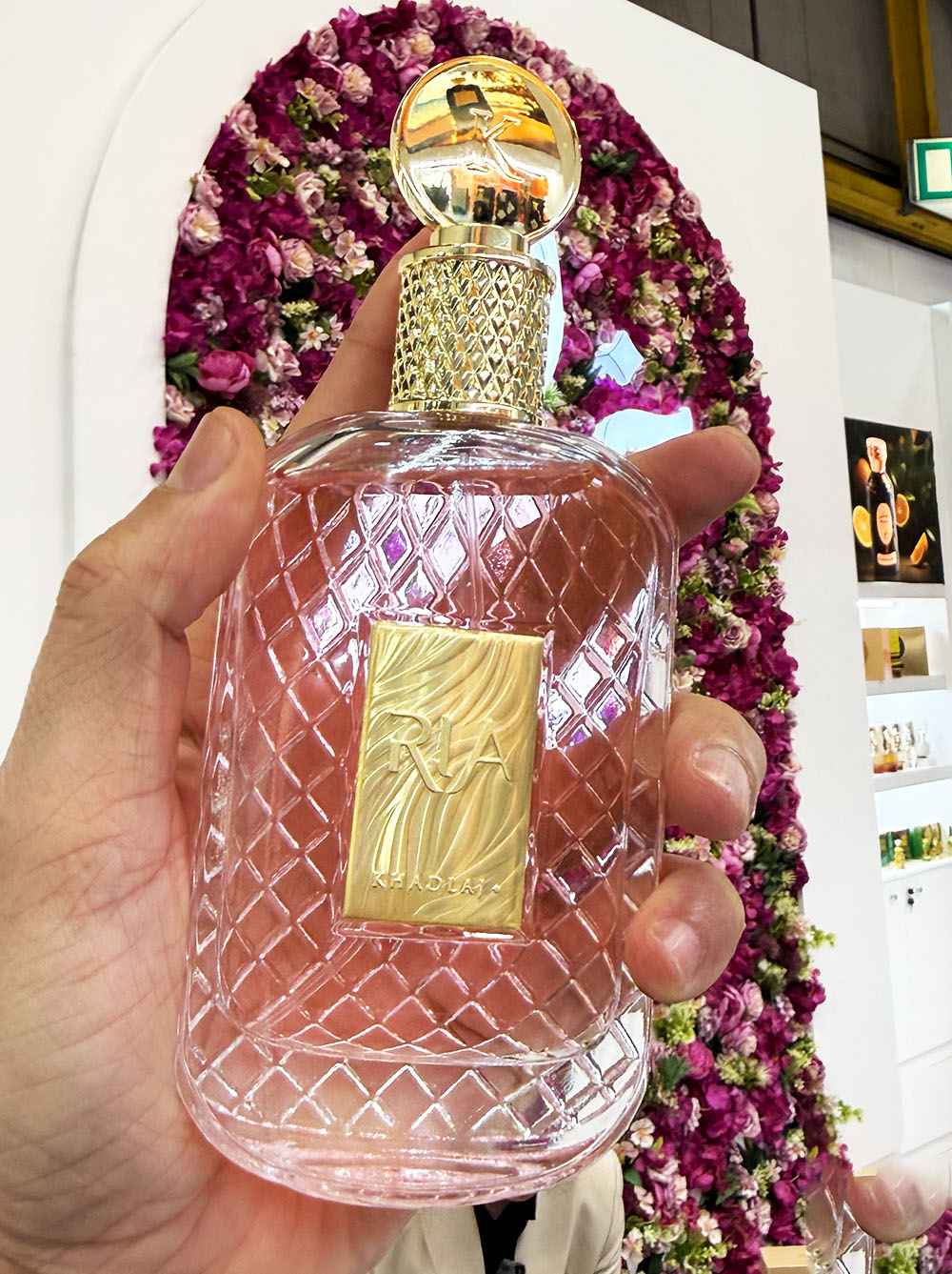 Khadlaj Ria modelo vestida de forma cuidada sujetando el perfume en escena urbana