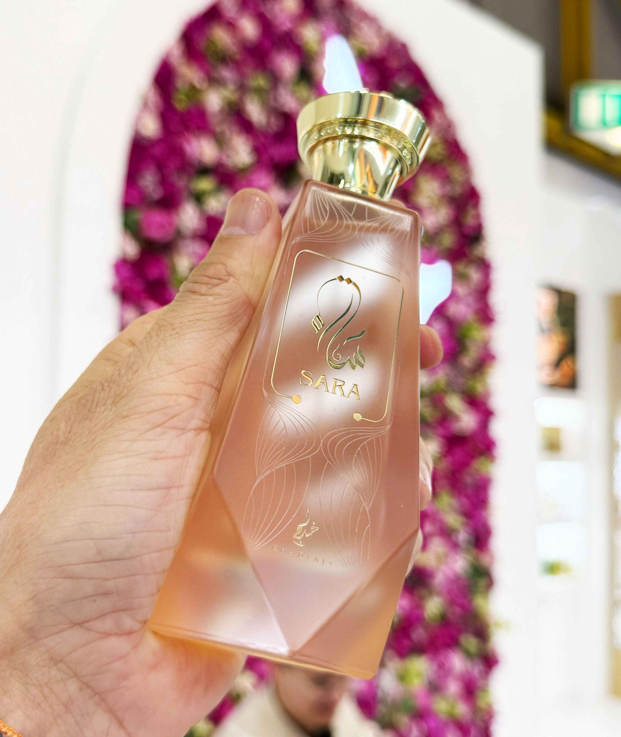 Khadlaj Sara modelo vestida de forma cuidada sosteniendo el perfume en primer plano