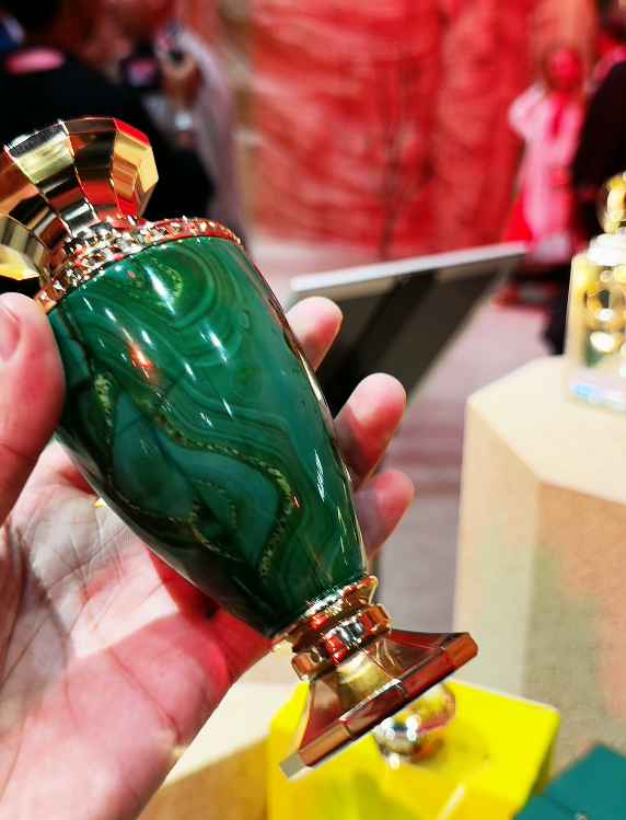 French Avenue Jade Green escena publicitaria con modelo elegante sujetando el perfume en entorno verde